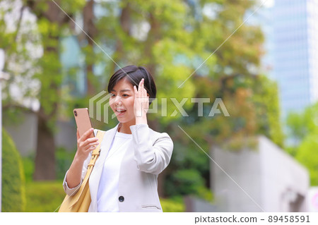 A woman who looks at her smartphone and notices a mistake in her work and holds her head down 1 89458591