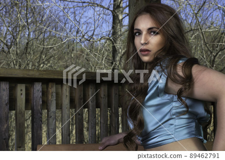 young woman outside wearing blue silk camisole hand on hip at the park young woman outside wearing blue silk camisole hand on hip at the park 89462791