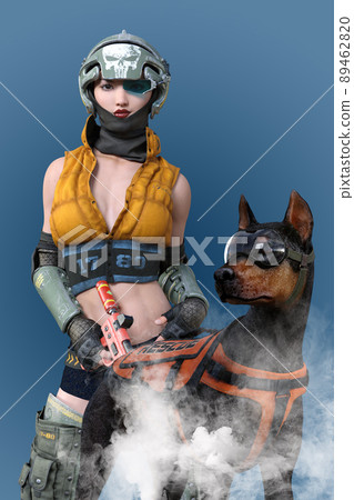 一個穿著黃色夾克和骷髏頭盔的女人，以及一個戴著護目鏡和裝備的強壯的杜賓犬。 89462820