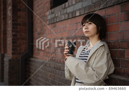 A pensive woman with a drink in her hand 89463660
