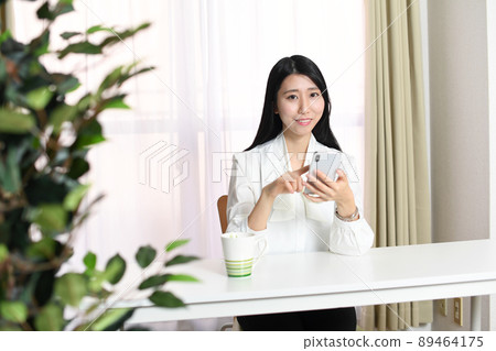 有智能手機的一個微笑的亞裔婦女 89464175