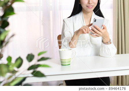 有智能手機的一個微笑的亞裔婦女 89464176