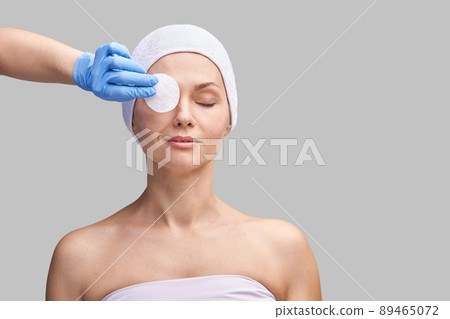 Pure skin care mature beauty portrait. Demakeup using cotton pad. Cosmetology 89465072