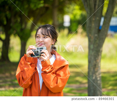 一位年輕女子在陽光明媚的日子裡用複古膠卷相機在戶外拍照 89466301