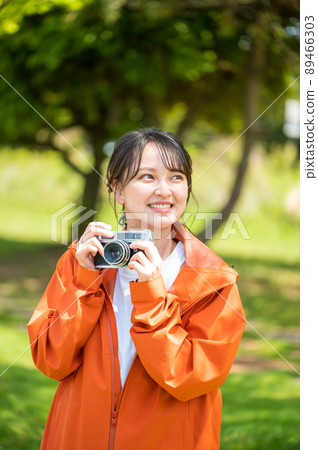 一位年輕女子在陽光明媚的日子裡用複古膠卷相機在戶外拍照 89466303