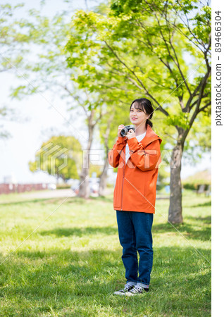 一位年輕女子在陽光明媚的日子裡用複古膠卷相機在戶外拍照 89466304