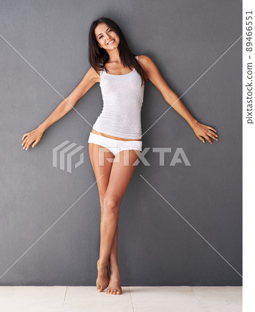 Complete confidence. Full-length shot of a beautiful young woman standing with her arms outstretched against a gray wall. Complete confidence. Full-length shot of a beautiful young woman standing with her arms outstretched against a gray wall. 89466551