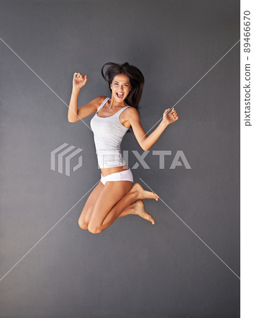 You've got to make life exciting. Full-length shot of a happy young woman jumping against a gray background. 89466670