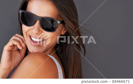 Brimming with confidence. Shot of a beautiful young woman wearing sunglasses. Brimming with confidence. Shot of a beautiful young woman wearing sunglasses. 89466671
