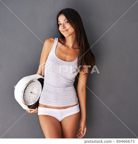 Healthy confidence. Shot of a beautiful and healthy young woman holding a scale. Healthy confidence. Shot of a beautiful and healthy young woman holding a scale. 89466673