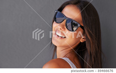Looking confident in those shades. Shot of an attractive young woman wearing sunglasses. Looking confident in those shades. Shot of an attractive young woman wearing sunglasses. 89466676
