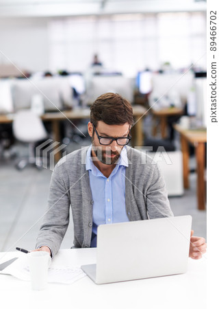 Focused on the finer details. Shot of a handsome young businessman using a laptop in a casual working environment. 89466702