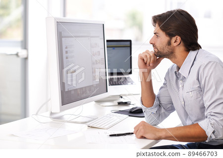 Turning his ideas into reality. Shot of a handsome man working on a computer in an office. 89466703