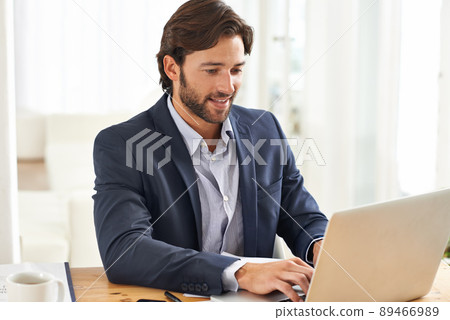 Work is a breeze today. A handsome businessman working on his laptop. Work is a breeze today. A handsome businessman working on his laptop. 89466989