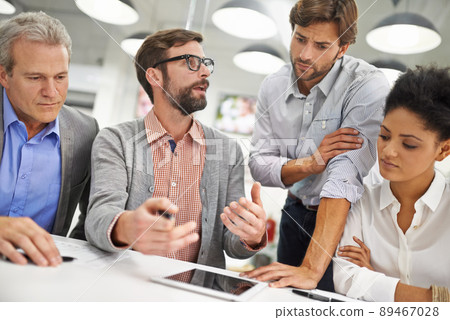 Explaining the team's progress. Shot of a group of young professionals working at a desk in an office. 89467028