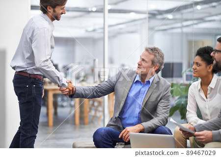 Welcome to the team young man. Shot of a two business professionals shaking hands in an office. Welcome to the team young man. Shot of a two business professionals shaking hands in an office. 89467029