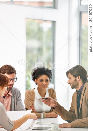 Offering a bit of business wisdom. A group of businesspeople going over some plans together in an office. 89467030
