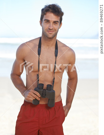 Hes looking out for danger in the water. A handsome young lifeguard at the beach. Hes looking out for danger in the water. A handsome young lifeguard at the beach. 89469271
