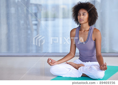 Finding inner peace. Shot of an attractive young woman meditating on an exercise mat. 89469356