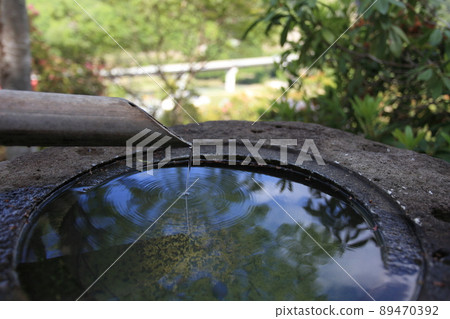 蹲，築貝的上身，竹筒上滴下的水珠在長足的表面形成了一個環形圖案，天空和樹木的葉子倒映在水鏡中，側身。 89470392