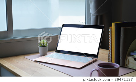 Laptop computer with white empty display, coffee cup and books on wooden table. Laptop computer with white empty display, coffee cup and books on wooden table. 89471157