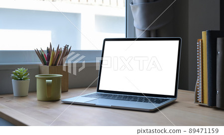 Computer laptop with white empty screen, coffee cup and stationery on wooden table. Computer laptop with white empty screen, coffee cup and stationery on wooden table. 89471159