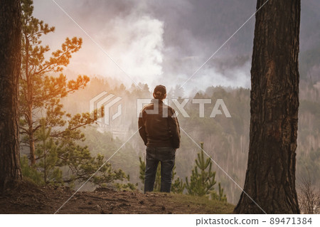 a man looks at a burning fire in the forest. tourist or forest arsonist 89471384