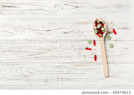 Vitamin capsules in a wooden spoon on a colored background. Pills served as a healthy meal. Drugs, pharmacy, medicine or medical healthycare concept Vitamin capsules in a wooden spoon on a colored background. Pills served as a healthy meal. Drugs, pharmacy, medicine or medical healthycare concept 89474613