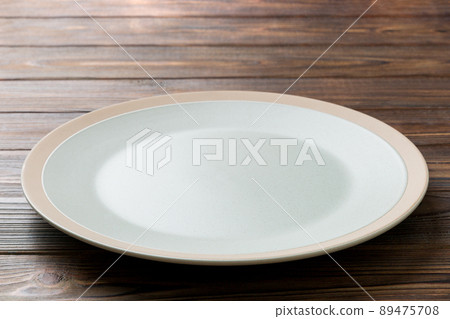 Perspective view of empty light plate on wooden background. Empty space for your design Perspective view of empty light plate on wooden background. Empty space for your design 89475708