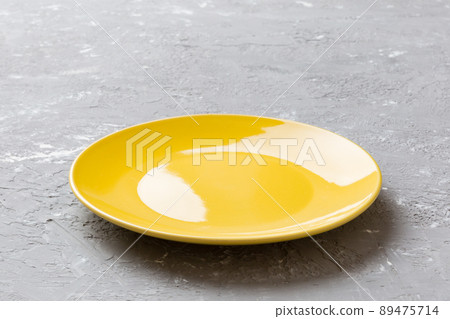 Perspective view of empty yellow plate on cement background. Empty space for your design 89475714