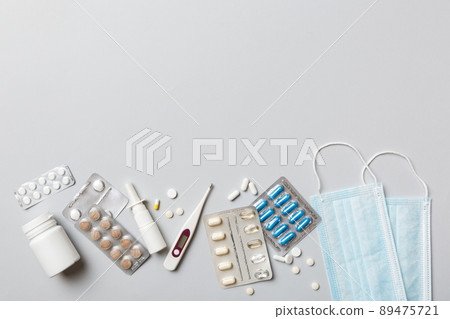 Protective face masks or surgical masks, medicine pills and thermometer on table background. Coronavirus disease. Corona virus concept. Space for text Protective face masks or surgical masks, medicine pills and thermometer on table background. Coronavirus disease. Corona virus concept. Space for text 89475721
