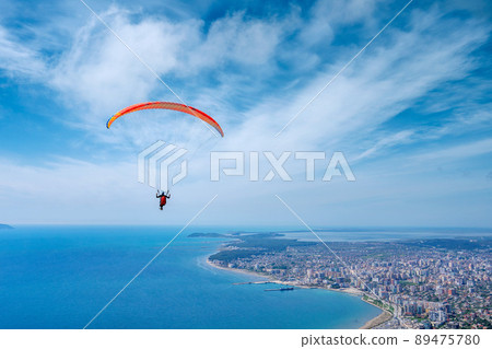 Athlete paragliding against the backdrop of a cloudy sky over the city on a summer day. Albania Athlete paragliding against the backdrop of a cloudy sky over the city on a summer day. Albania 89475780