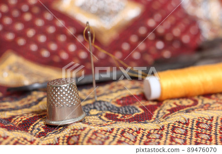 Golden Thread and Thimble on Vintage Fabric From The Middle East Golden Thread and Thimble on Vintage Fabric From The Middle East 89476070