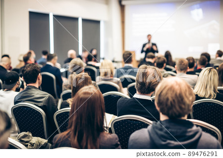 Speaker giving a talk in conference hall at business event. Rear view of unrecognizable people in audience at the conference hall. Business and entrepreneurship concept. 89476291