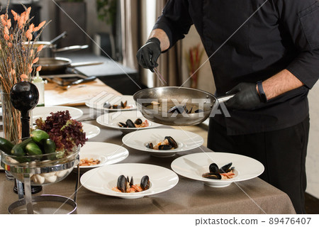 chef prepares carrot cream soup with seafood in a restaurant 89476407