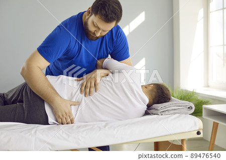 Male physiotherapist help client with backache 89476540
