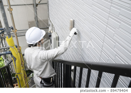 A painter who paints the exterior walls of a detached house with a brush A painter who paints the exterior walls of a detached house with a brush 89479404