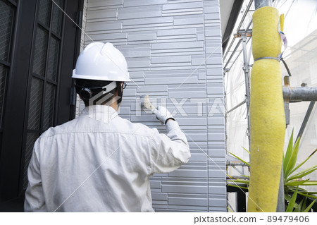 A painter who paints the exterior walls of a detached house with a brush 89479406