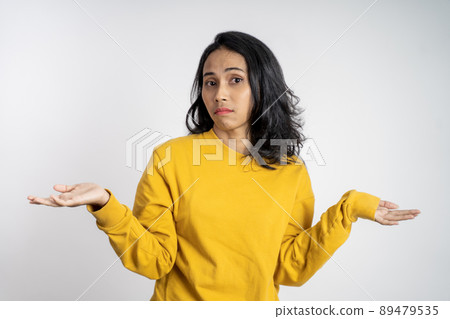 asian woman opening two palms on isolated background feeling uncertain asian woman opening two palms on isolated background feeling uncertain 89479535