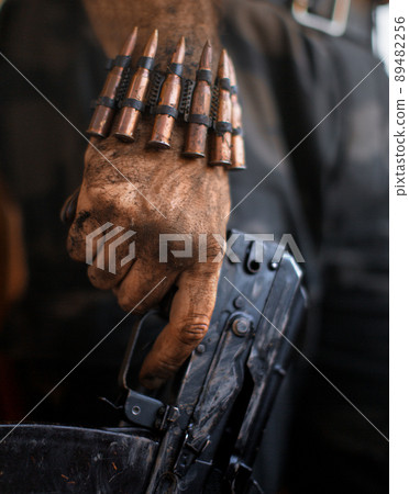 Dirty rebel hand with a machine gun and a bracelet with machine-gun cartridges. Dirty rebel hand with a machine gun and a bracelet with machine-gun cartridges. 89482256
