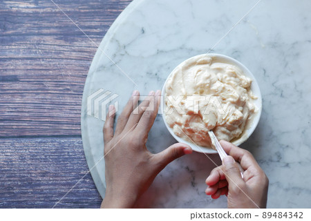 Top view of man's hand eating fresh yogurt from a bowl Top view of man's hand eating fresh yogurt from a bowl 89484342