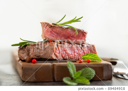 Grilled beef fillet steak with herbs and spices on dark table close up Grilled beef fillet steak with herbs and spices on dark table close up 89484918