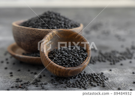 Wooden bowls of dry black lentils beans on grey table close up, protein source for vegetarian diet 89484932