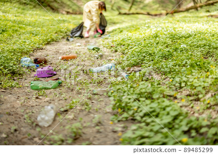 Person collecting scattered plastic garbage on nature 89485299