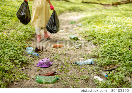Person collecting scattered plastic garbage on nature 89485300
