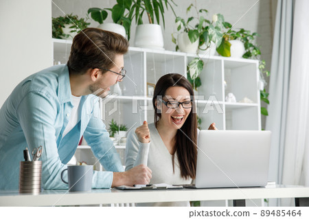 A woman and a man are happy about a successful deal in the office. 89485464