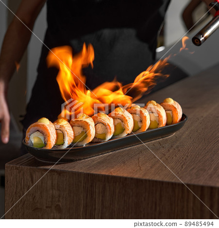 Restaurant Chef cook preparing salmon filet flambe in open kitchen. 89485494