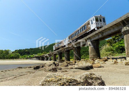 JR九州日南線地方特快海幸山幸行駛在宮崎縣日南市山王的熊谷川大橋上，在日南海岸上鋪滿了湛藍的天空 89486328