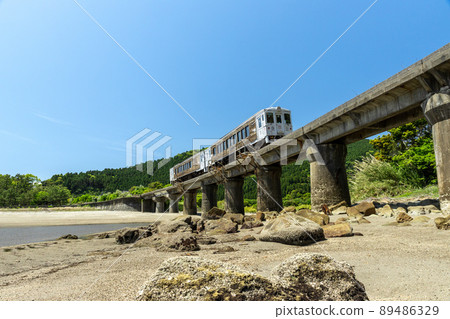 JR Kyushu Nichinan Line Local Limited Express Umisachi Yamasachi running on the Kumagaya River Bridge in Sanno, Nichinan City, Miyazaki Prefecture, where the clear blue sky spreads on the Nichinan coast 89486329