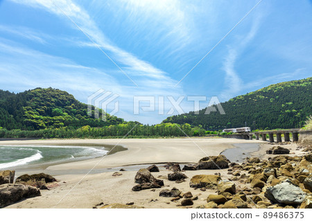 JR Kyushu Nichinan Line Local Limited Express Umisachi Yamasachi running on the Kumagaya River Bridge in Sanno, Nichinan City, Miyazaki Prefecture, where the clear blue sky spreads on the Nichinan coast 89486375